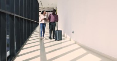 Koridorda yürüyen bavullu Afrikalı çift. Meslektaşlar gayri resmi konuşuyorlar, konferans için birlikte uçuyorlar, projeyi tartışıyorlar. Eşler konuşuyor, havaalanı terminali boyunca ortak tatil planlıyorlar.
