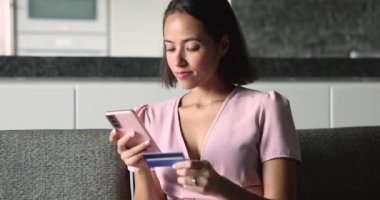 Mutlu bir kadın kapat, kanepeye otur, akıllı telefon ve kredi kartı kullanarak online alışverişin tadını çıkar, internetten alışveriş yap, hediyeler seç, hizmet başvurusu al. Güvenli banka hizmetleri, ödeme güvencesi