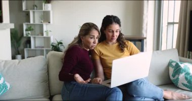 İki kadın, anne ve kız online alışverişi dizüstü bilgisayarla tartışır, kanepede oturup pazar yeri uygulaması üzerinden satın alan moda sitelerine bakar, e-servis veya ticari teklifi dikkate alırlar. Ticaret.