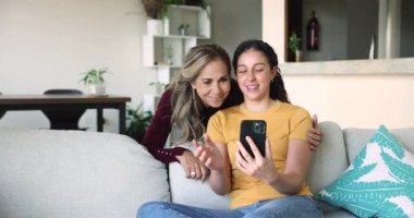 Yetişkin bir kadın. Yetişkin kızı cep telefonu ekranına bakıyor. Selfie ya da video görüşmesi yapıyor. Eğlence, eğlence ve uzak iletişim için modern cihaz kullanımı