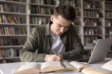 Pozitif çalışkan öğrenci taslak, notlar, makale, kompozisyon, Webinar özet, üniversite kütüphanesinde okumak, açık kitaplarla ve dizüstü bilgisayarla çalışma,