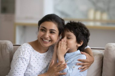 5 'in oğlu gülümseyen Hint anne kulağına fısıldıyor, sırlarını paylaşıyor, dedikodu yapıyor, mutlu genç anne ve sevimli çocuk keyifli sohbetler, iyi ilişkiler, güven ve aile kavramı.