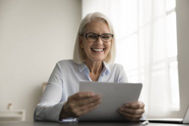 Gözlüklü, çalışma masasında evrak tutan, yasal kağıt okuyan, gülümseyen, gülen, gözlüklü, son sınıf iş kadını. Mutlu kadın sigorta sözleşmesini gözden geçiriyor.