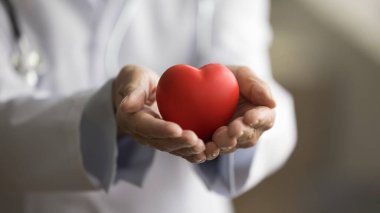Kırmızı kalp tutan doktor kadının elleri, sevginin sembolü, hastaya insan desteği, sağlık sigortasının desteklenmesi, sağlık hizmetleri için erken kontrol, kardiyolog yardımı. Nesneye yaklaş