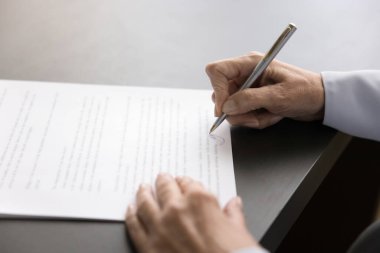 Olgun bir kadın belge imzalar, kalem kullanır, yasal kağıt yazar, sigorta anlaşmasına imza atar, yatırım sözleşmesi yapar, gayrimenkul satın alır. Kadın ellerine yakın dur.