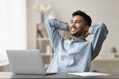 Gülümseyen Hintli adam işten sonra tatmin oluyor rahatlamak için ellerini başının arkasına koyup sandalyeye yaslanıyor, projeyi bitiriyor, internette para kazanıyor, ara veriyor, başka tarafa bakıyor. Amaçlar, duraksama, iyi iş.