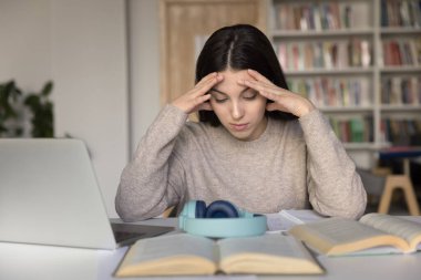 Liseli kız kütüphanede ders kitaplarıyla oturuyor, sınavlara hazırlanıyor, matematik ödevini düşünüyor, okuyor, kafasını fazla çalıştırıyor, çalışmaktan ya da çalışmaktan yorgun hissediyor. Fazla bilgi yüklenmesi