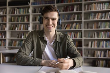 Videocall katılımcısı, adam hocasıyla çevrimiçi çalışmaya katılıyor, konuyu öğreniyor, yeni bilgiler ediniyor modern teknoloji kullanıyor üniversite kütüphanesinde masada oturuyor kameraya bakıyor. Eğitim, sanal buluşma etkinliği