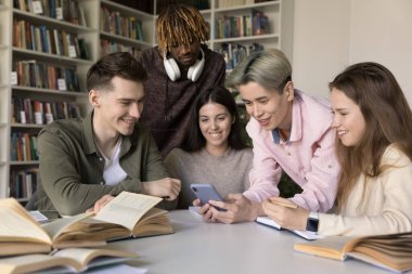 Bir grup çekici çok ırklı öğrenci video izliyor, kütüphanede toplanan ve modern akıllı telefon kullanılarak yapılan çalışmalardan uzaklaştırılan yeni ve eğlenceli mobil uygulamaların tadını çıkarıyorlar. Z jenerasyonu, eğlence
