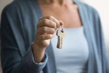 Ev, yeni ev, ev anahtarlarını gösteren bir kadın. Son sınıf sahibi kadın, satıcı, emlakçı gayrimenkul yatırımını, emlak alımını, kiralama hizmetini destekleyen