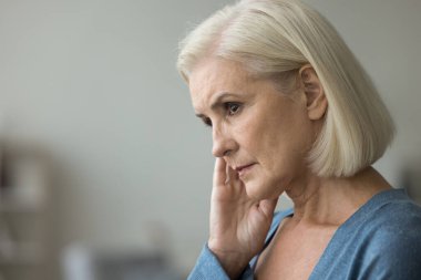 Ciddi, düşünceli, yaşlı, sağlık sorunları için endişelenen yaşlı bir kadın. Emeklilik hakkında düşünüyor, kuru cilde dokunuyor, yüzünü çeviriyor, yüzünü çeviriyor, depresyona giriyor. Yan taraftaki portre