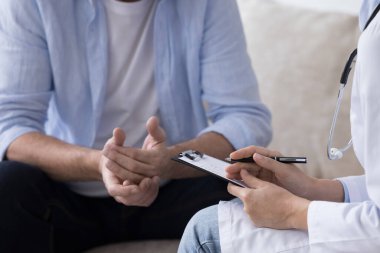 Görüş açısını kapatın. Klinikte erkek hasta sağlık sorunlarını paylaşıyor, kanepede oturup kadın pratisyen hekimle konuşuyor, sağlık danışmanlığına başvuruyor, profesyonel tıbbi danışmanlık alıyor. Sağlık Hizmetleri