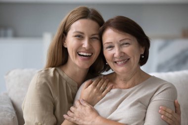 Head shot beautiful millennial daughter hugging her middle-aged pretty mother, having attractive appearance, optimistic mood. Two-generational women portrait, family bond and support, close up shot clipart