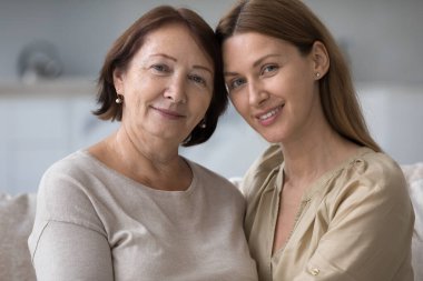 Sevgili orta yaşlı annenin, büyümüş güzel kızını kucakladığı portreyi yakından çek. Genç ve yaşlı kadınların aileleri birlikte vakit geçirir, destek olur, sevgi ve ilgi gösterirler.