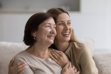 İki nesildir kucaklaşan güzel beyaz kadınlar koltukta oturup uzaktan bakıyorlar. Mutlu annelik, aile bağları ve anlayış, anne ile yetişkin kız arasındaki ahenkli ilişkiler