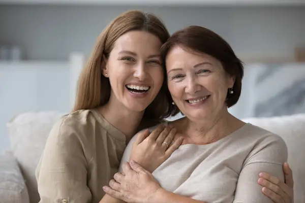 stock image Head shot beautiful millennial daughter hugging her middle-aged pretty mother, having attractive appearance, optimistic mood. Two-generational women portrait, family bond and support, close up shot