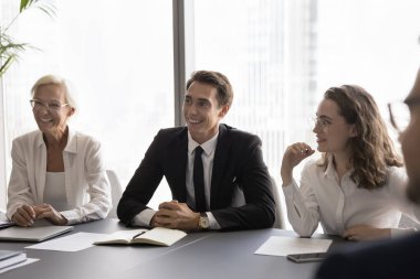 Neşeli iş ortakları ofiste resmi bir toplantı yapıyorlar. Bir grup gülen orta yaşlı ve genç iş adamı, şirket çalışanları modern konferans odasındaki masada oturmaktan keyif alıyorlar.
