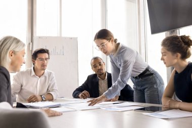 Kadın takım lideri konferans odasında çeşitli takım arkadaşlarıyla işbirliği yapıyor, grup toplantısında iş görüşmelerini tartışıyor, satış sonuçlarını paylaşıyor, planlama stratejisini paylaşıyor, ofisteki brifinge katılıyor.