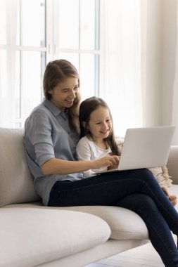 Çekici bir anne hafta sonunu tatlı küçük kızıyla evde geçirir, oturma odasında kanepeye oturur, dizüstü bilgisayar kullanır, internetten alışveriş yapar, bilgisayardan eğlenceli videolar izler, internette dinlenir.