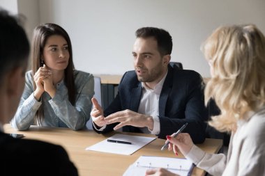 Ciddi iş adamları toplantı masasında oturuyor, iş ortaklarıyla toplantıda konuşuyor, anlaşma şartlarını tartışıyor, müzakere yapıyor, planlama geliştirme stratejisi uyguluyor, odaklanmış erkek liderler fikir ve çözümleri paylaşıyor.