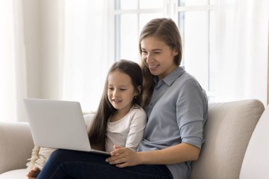 Anne ve küçük kızı hafta sonu tatillerini internette, dizüstü bilgisayarda, kanepeye oturup cihaz ekranına bakarak, eğitim programını izleyerek, pazardan alışveriş yaparak, e-ticaret hizmetlerinden ve çevrimiçi çizgi filmlerden zevk alarak geçiriyorlar.