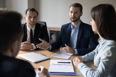 Takım elbiseli genç işadamı müşterilerle resmi toplantıda konuşma yaptı, stratejiyi açıkladı, ortak proje planladı, fikirleri paylaştı, müşterileri veya yatırımcıları işbirliğine ikna etti. İş, müzakere