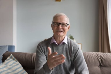 Olgun bir adam kanepeye oturup görüntülü konuşma ile iletişim kurar. Sunbaenim video konuşması yapıyor, konuşma yapıyor, haberleri paylaşıyor, modern teknoloji ve interneti kullanarak yurtdışında yaşayan aileyle uzaktan sohbet ediyor.