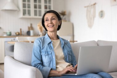 Mutlu serbest çalışan kadın evinde dizüstü bilgisayarda çalışıyor, internet iletişiminin tadını çıkarıyor, internet üzerinden haberleşmeyi paylaşıyor, e-ticaret sitesi üzerinden sipariş veriyor. Eski nesil ve modern teknoloji kullanımı