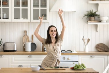 Güzel genç kız, mutfakta sağlıklı yiyecekler hazırla, enerjik şarkılar dinle, dans et, favori müziğe geç, vejetaryen, sağlıklı, evde doğal yemekler pişir, eğlen. Aşçılık, hobi