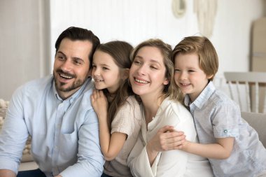 Dost canlısı hayalperest çift ve çocuklar yeni evdeki kanepede dinleniyor ebeveynler iki küçük çocukla vakit geçiriyorlar, eğleniyorlar, sevgi ve ilgi gösteriyorlar. İki kuşağın aile portresi