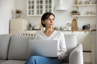 Ciddi odaklanmış olgun bir kadın kucağında defteriyle kanepeye oturur, yana bakar, metni düşünür, yeni yazı için fikir arar. Blog yazma, eski nesil ve modern teknoloji kullanımı öğrenim, çalışma veya satın alma için