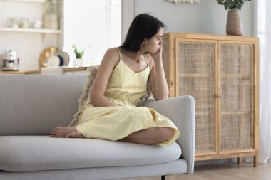 Üzgün düşünceli kadın kanepeye oturur, ilişkileri, sorunları düşünür, üzgün hisseder, düşüncelerde kaybolur yalnız görünür, depresif olur, evde yalnız başına sıkılır. Özel hayat sorunları, ayrılık.