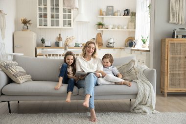 İki sevimli çocuk, anneleri kanepede otururken, çocukları eğlendirmek için ilginç bir kitap okuyor ve evde vakit geçiriyorlar. Hobi, iyi büyüme, gelişme ve eğitim