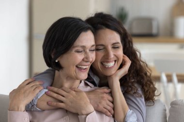Mutlu, olgun anne ve yetişkin çocuk kadın sarılıyor, gülümsüyor, gülüyor, omuzlarına dokunuyor, dişlek gülümsemeler takınıyor, birlikte zaman geçiriyorlar, aile hafta sonunun keyfini çıkarıyorlar.