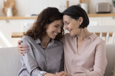 Mutlu ve olgun bir anne duygusal alınları olan güzel yetişkin bir kadına sarılıyor, gözleri kapalı gülüyor, stres atıyor, eğleniyor, aile ilişkilerinden keyif alıyor.