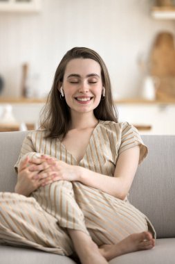 Huzurlu genç bir kadın kaliteli sesten hoşlanır, modern kablosuz kulaklıklarla gözleri kapalı müzik dinler, evde yalnız başına kaygısız vakit geçirir, hobi ve favori şarkı, dikey çekim
