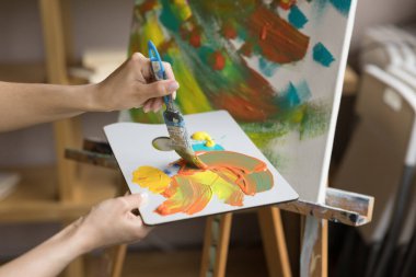 Kapalı kadın ressam palet ve boya fırçasını tutuyor akrilik boyaları karıştırarak eşsiz renkler yaratıyor, kişisel tarzını geliştiriyor ve kendine özgü sanat eserleri yaratıyor. Profesyonel sanatçı iş akışı, yaratıcı hobi