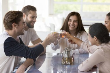 Beş güzel milenyum kızı ve erkekleri kafe masasında oturup çay fincanlarını tokuşturarak tanışmamızı kutluyorlar. En iyi çok ırklı arkadaşlar, birlik ve dostluk göstererek, yaşam boyu süren etkinliği kutluyor.