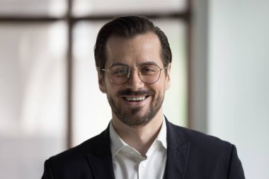 Gözlüklü ve takım elbiseli güler yüzlü iş adamının resmi, kameraya bakın. Şirket sahibi memnuniyet duyuyor ve mesleki başarılarından gurur duyuyor. Lider proje portresi, iş tutkuları