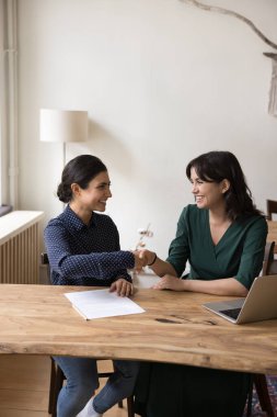 İki genç çok ırklı kadın, ofis çalışanları başarılı bir iş ya da iş görüşmesinden sonra modern ofiste el sıkışıyor, işbirliğinden tatmin oluyor, iyi bir anlaşma yapıyor, sözleşme imzalıyor, toplantıyı başlatıyor ya da bitiriyor.