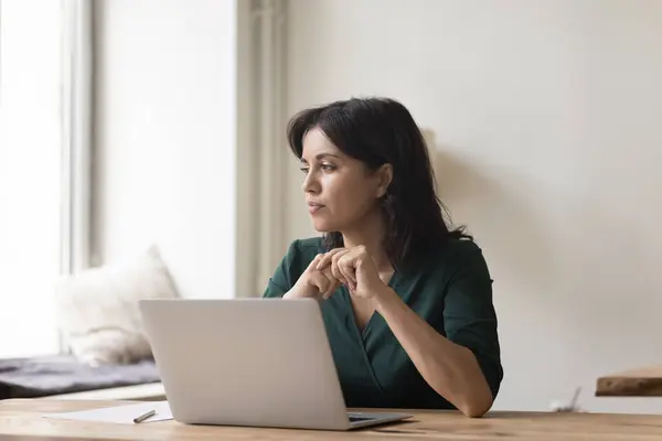 stock image Serious woman sit at workplace desk with laptop starting aside, search solution stuck with difficult task, faced with business challenge, thinks over task, lack of understanding, motivation or ideas