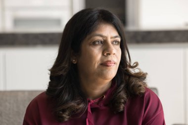 Düşünceli son sınıf Hintli kadın rahat rahat koltukta oturuyor, derin düşüncelere dalıyor, yaşlanan sağlık sorunlarını düşünüyor, kendini yalnız ve depresif hissediyor. Düşünceli olgun kadın model portresi