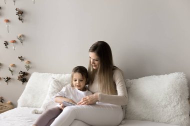 Sevgi dolu anne ilginç bir kitap okudu, küçük zeki kıza büyüleyici bir tarih, rahat bir yatakta birlikte oturmak, hobi olarak eğlenmek, hikaye anlatmak. Ebeveynler çocuklarına evde boş vakitlerde okumayı öğretir.