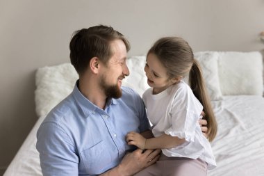 Mutlu küçük kız sevgi dolu baba kucağına oturur, yatak odasında yatağında gündüz uykusuna yatar. Baba, sevimli kızını gıdıklıyor, birlikte kaygısız zaman geçiriyor, koşulsuz sevgiyi hissediyor, okşuyor.