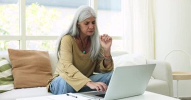 Evde dizüstü bilgisayarda çalışan, daktilo kullanan, online finansal uygulama kullanan, kağıt belgelere notlar yazan, muhasebe işlemleri yapan,