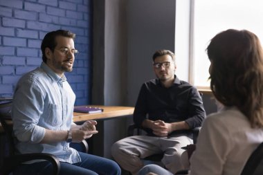 Genç başarılı şirket lideri modern yönetim kurulunda iki çalışanla konuştu, ortak görevleri açıkladı, çalışma haftasını planladı. Ofisteki meslektaşlarım yeni projeyi değerlendirip ticari anlaşmayı tartıştılar. Takım iletişimi