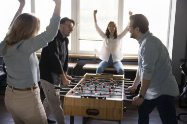 Neşeli iş adamları, takım arkadaşları tatilde ofiste masa futbolu oynuyor. Bir grup iş arkadaşı işten kaytarıyor, masa başı futbol maçlarında yarışıyorlar, gülüyorlar, tezahürat yapıyorlar, destekliyorlar.