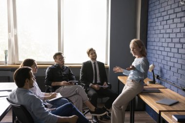 Orta yaşlı kadın lider, görevi açıkla, projeyi tartış, yeni yaratıcı fikir ya da plan sun. Olumlu yaşlı koç genç çalışanlara seminer veriyor, takım kurma, danışmanlık, iş dünyası.