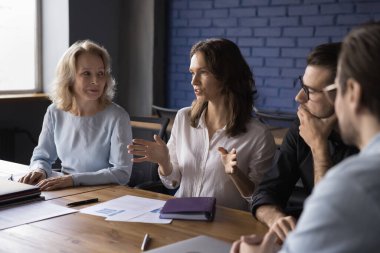 Genç ve çekici bayan takım lideri modern ofiste antrenman yapıyor, seminerde seyircilere ders veriyor. Ciddi bir iş kadını toplantı odasında grup brifinginde proje planını tartışıyor. İş, takım çalışması, müzakere