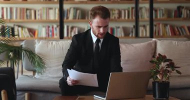 Kütüphanede dizüstü bilgisayar kullanan, lobideki koltukta oturan, ortak çalışma alanı olan, yasal belgeleri kontrol eden, bilgisayarda danışmanlık yapan, resmi takım elbiseli, Kafkasyalı genç bir işadamı.